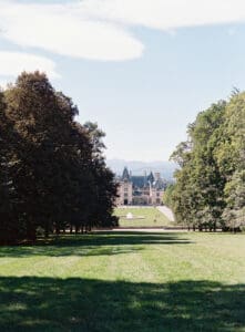Biltmore Weddings – Marcos and Gaby Far away shot of Biltmore Estate, lush trees in foreground.