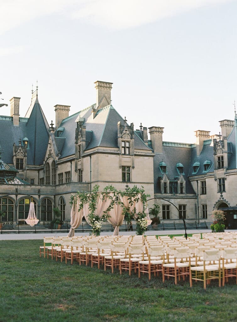 legant outdoor wedding ceremony setup at the Biltmore Estate with draped floral arch and chandeliers.