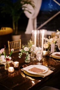 Biltmore Weddings – Marcos and Gaby Intimate candlelit wedding table with gold flatware, floral arrangements, and personalized place settings at the Biltmore Estate.