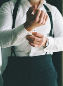 Biltmore Weddings – Marcos and Gaby Close up of groom adjusting cufflinks while wearing a tuxedo with suspenders.