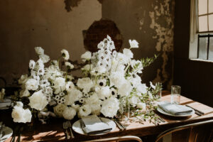 Rhubarb Asheville Wedding Planned by Terran Ward Close-up of rustic-styled wooden reception table set-up featuring white florals. Wedding planned by Asheville wedding planner Terran Ward — bold editorial mountain wedding design.
