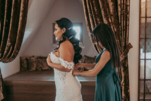Daniela and Angelo Wedding Grand Bohemian Asheville Bride being buttoned into her lace gown. Wedding Planned by Terran Ward at The Grand Bohemian Asheville