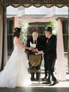 Grand Bohemian Asheville Wedding_Carly and David Bride and groom standing before the officiant, happily, under a tent at the Grand Bohemian Asheville. Wedding Planned by luxury Asheville Planner Terran Ward