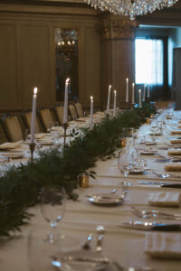 Grand Bohemian Asheville Wedding_Carly and David Close-up of long wedding reception table featuring greenery and candlesticks in the center on a white table cloth at the Grand Bohemian Asheville. Wedding Planned by luxury Asheville Planner Terran Ward