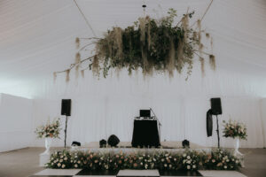 Biltmore Estate Asheville Wedding_Heather + Ben Stage set-up with elegant florals in front of the stage and a floral chandelier above it. Wedding planned by Asheville wedding planner Terran Ward — bold editorial mountain wedding design.
