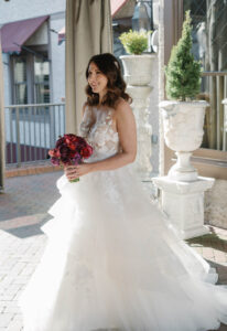 Grand Bohemian Asheville Wedding_Carly and David Image of the bride in her white lace gown holding a red bouquet under a tent at the Grand Bohemian Asheville. Wedding Planned by luxury Asheville Planner Terran Ward