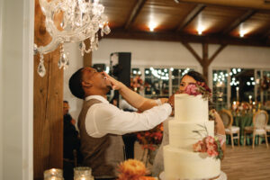 Mountain Wedding – Kaitlyn and Eric Bride smudging a small piece of cake into the groom's face. Wedding planned by Asheville wedding planner Terran Ward — bold editorial design setup.