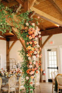 Asheville Mountain Wedding_Kaitlyn Eric Bold fall florals enveloping support arches indoors with elegant reception tables. Wedding planned by Asheville wedding planner Terran Ward — bold editorial design setup.