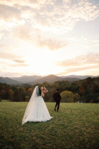 Bride and groom walking away from the camera; bride is closer to the camera. In front of sunset mountain views. Asheville wedding planner Terran Ward created sunset-driven timeline for mountain wedding