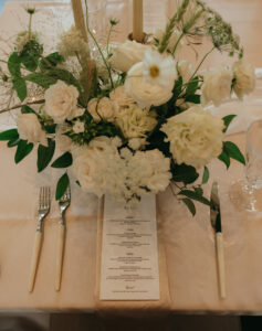 Chestnut Ridge Asheville Wedding_Mikaela + Jacob Wedding menu and floral centerpiece of white blooms and greenery at Chestnut Ridge reception. Wedding planned by Asheville wedding planner Terran Ward — bold editorial mountain wedding design.