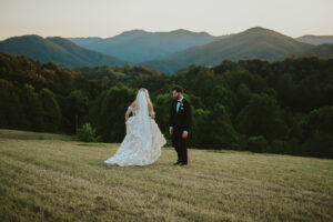 Bride walking to groom in front of sunset mountain views. Asheville wedding planner Terran Ward created sunset-driven timeline for mountain wedding