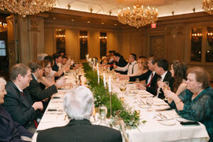 Grand Bohemian Asheville Wedding_Carly and David Long reception table with wedding guests seated at it under chandeliers at the Grand Bohemian Asheville. Wedding Planned by luxury Asheville Planner Terran Ward