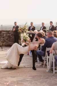Omni Grove Park Inn Weddings – Mr. and Mrs. Kelly Groom dips bride into a kiss during outdoor ceremony at Omni Grove Park Inn.