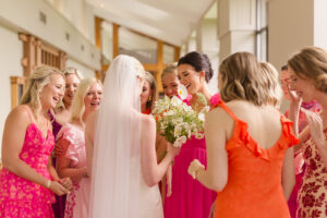 Omni Grove Park Inn Weddings – Mr. and Mrs. Kelly Bride shows her bouquet to bridesmaids in bright pink and orange dresses at the Omni Grove Park Inn.