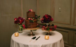Grand Bohemian Asheville Wedding_Carly and David Reception table with brown 2-tiered cake and red flowers at the Grand Bohemian Asheville. Wedding Planned by luxury Asheville Planner Terran Ward