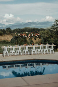 Tropical Wedding Planned by Terran Ward Tropical-inspired long reception table behind an in-ground pool. Wedding planned by Asheville wedding planner Terran Ward — bold editorial mountain wedding design.