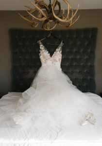 Grand Bohemian Asheville Wedding_Carly and David Wedding dress hanging from antler chandelier above bed at Grand Bohemian Asheville. Wedding Planned by luxury Asheville Planner Terran Ward