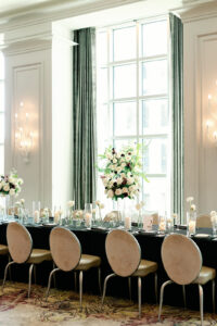 Grand Bohemian Hotel Asheville Wedding – Toree and Brandon Close-up of long reception table featuring white chairs, a dark green table cloth, and white and maroon floral centerpieces at the Grand Bohemian Hotel.