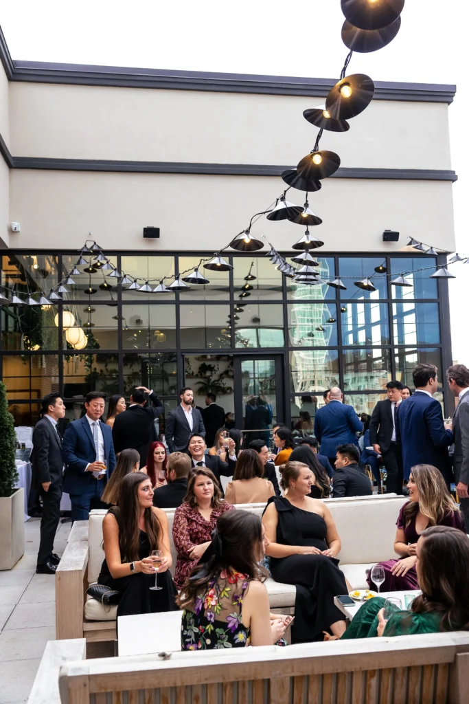 People gathered, sitting and standing, at the restoration hotel for a wedding reception. People are talking. Wedding planned by Terran Ward
