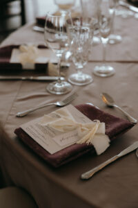 Close-up of reception table set-up featuring a maroon napkin, silverware, and glasses. Asheville wedding planner Terran Ward creating luxury weddings with a budget.