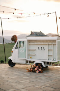 Small white catering truck with fall florals in front of back tires, sunset in background. Asheville wedding planner Terran Ward creating luxury weddings with a budget.