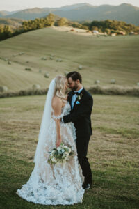 Bride and groom look at each other, their foreheads touching, in front of rolling mountains. The groom holds the bride. Asheville micro wedding — modern editorial setup by Terran Ward