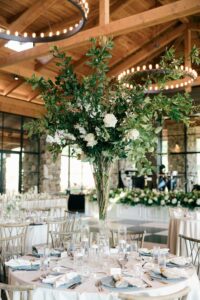 Close-up of a tall floral centerpiece and candles on a reception table at Omni Grove Park Inn. Asheville wedding planner Terran Ward creating luxury weddings with a budget.