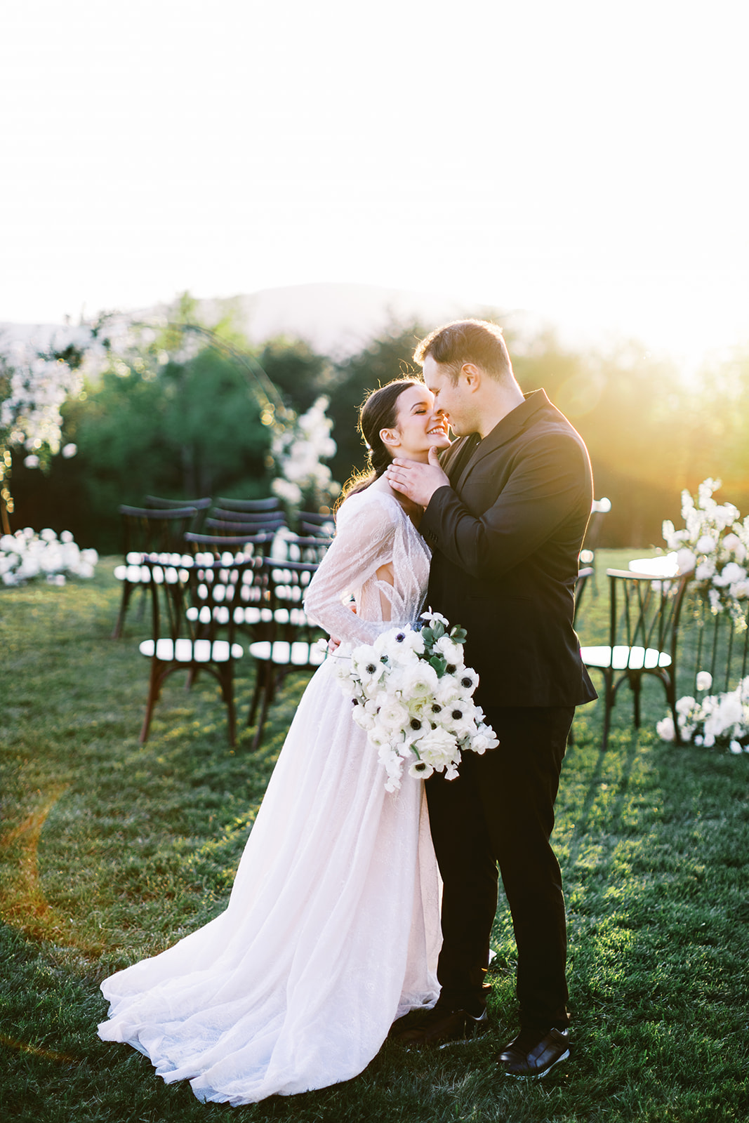 Bride and groom looking at each other, almost kissing. Groom has his hand resting on the bride's jaw. Micro wedding ceremony set up in the background. Asheville micro wedding — modern editorial setup by Terran Ward