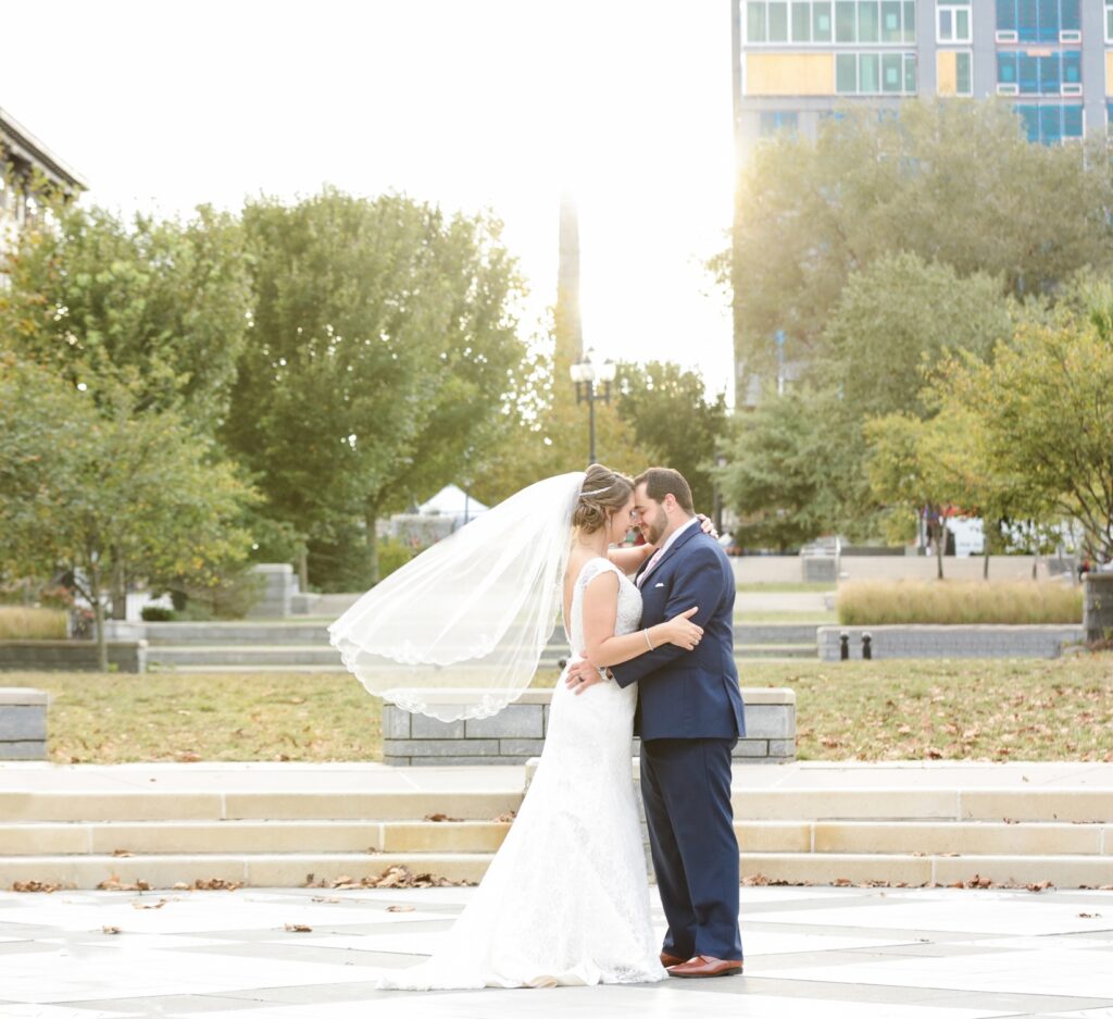 Bride and groom kissing at Pack Square Park, the bride's veil blowing in the wind.